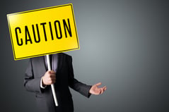 Businessman standing and holding a yellow caution sign in front of his head